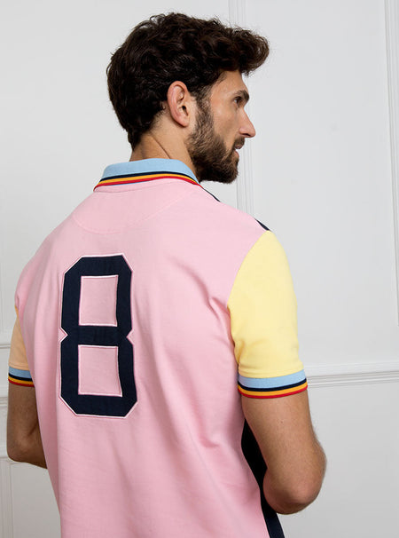 Man wearing navy based multicoloured panelled 100% cotton polo shirt with giant number 8 on pale pink back.